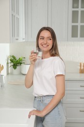 Woman drinking tap water from glass in kitchen