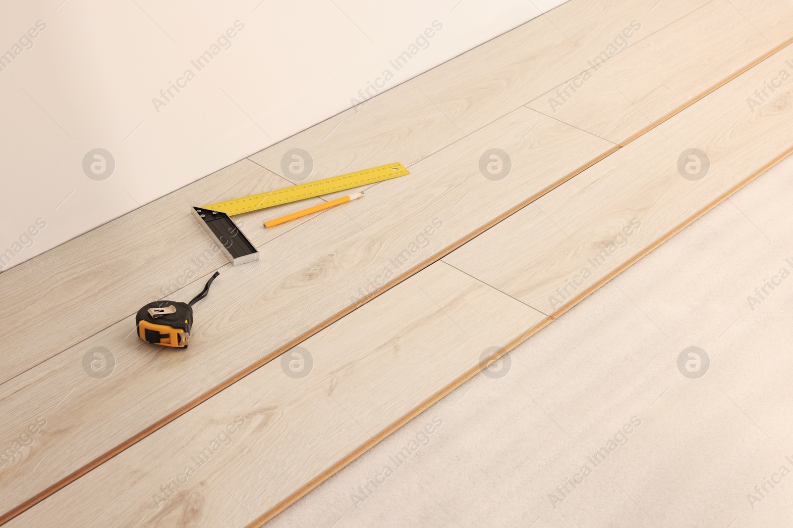 Photo of Parquet planks, ruler, pencil and measuring tape on floor in room prepared for renovation