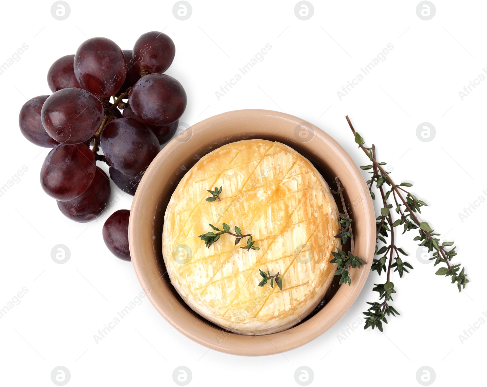 Photo of Tasty baked camembert in bowl, grapes and thyme on white background, top view