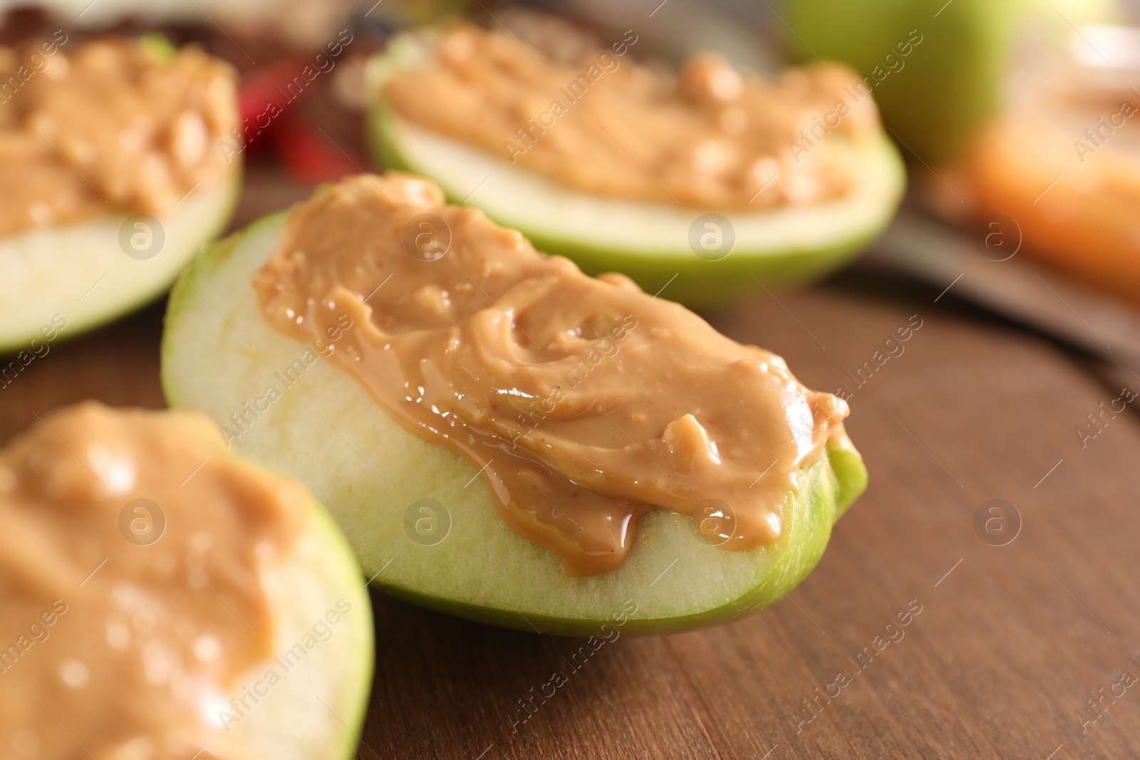 Photo of Slices of fresh apple with nut butter on wooden board, closeup