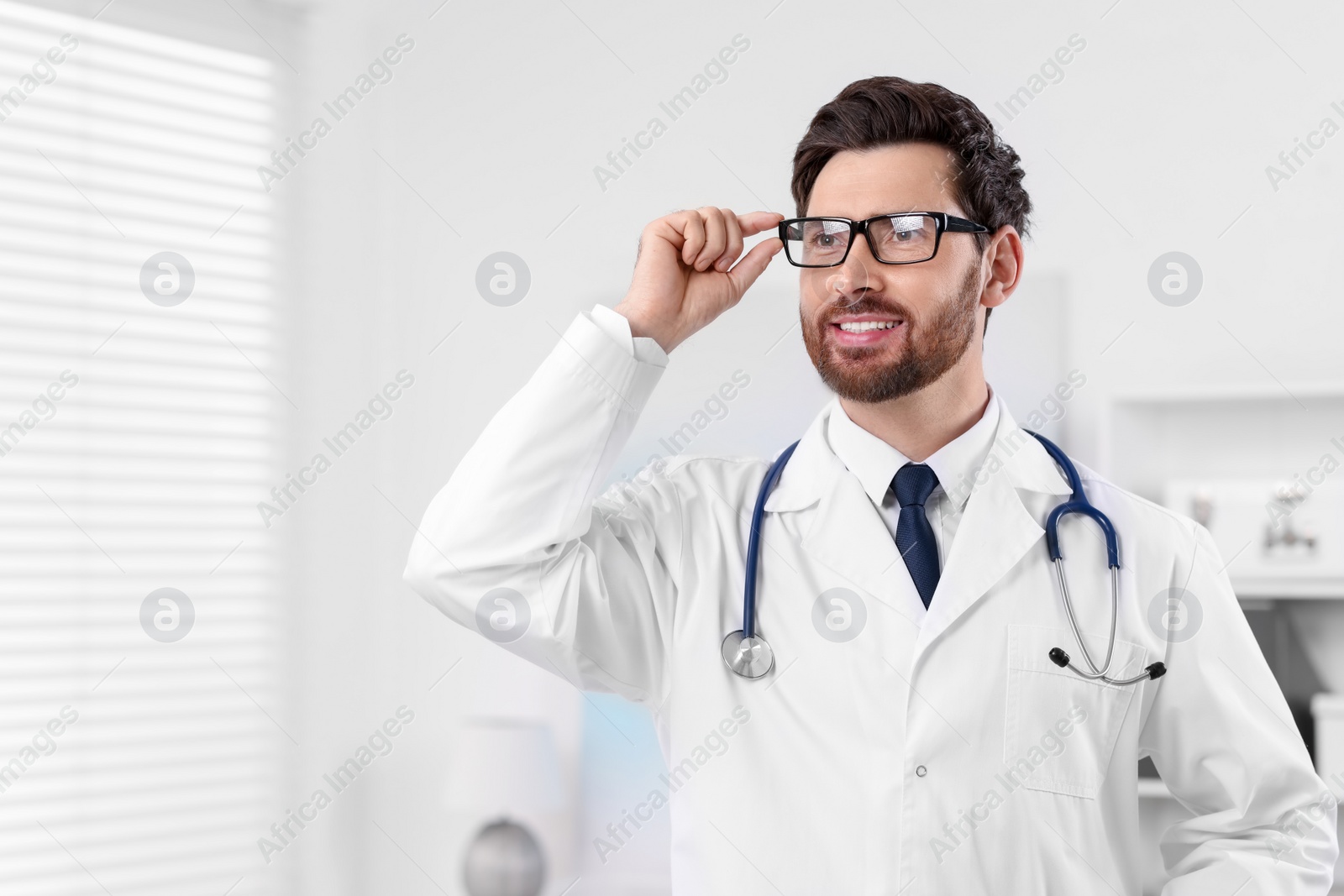 Photo of Medical consultant with glasses and stethoscope in clinic, space for text