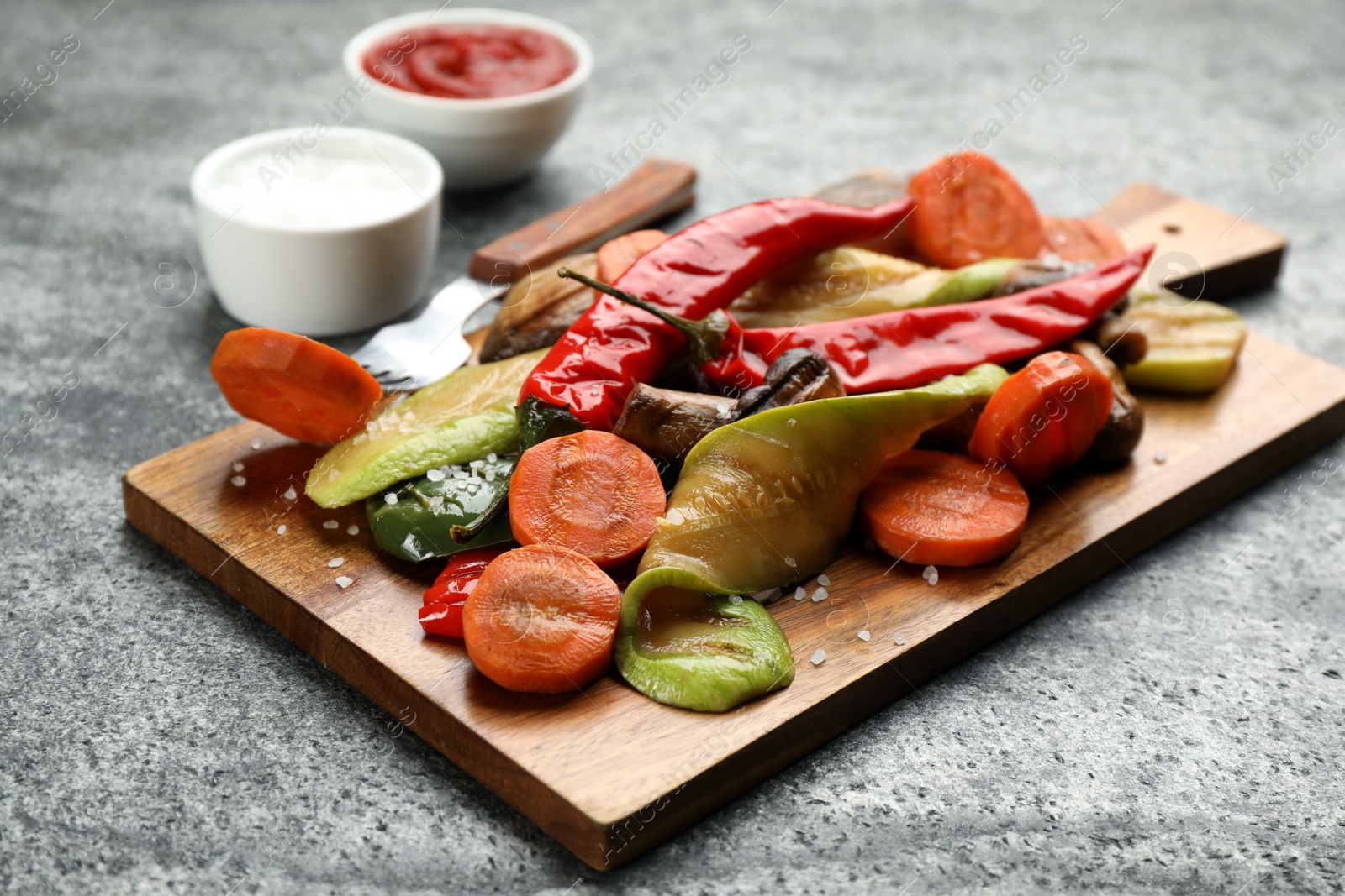 Photo of Wooden board with delicious grilled vegetables on grey table, closeup