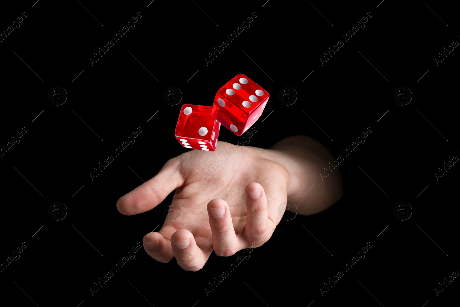 Image of Man throwing red dice on black background, closeup