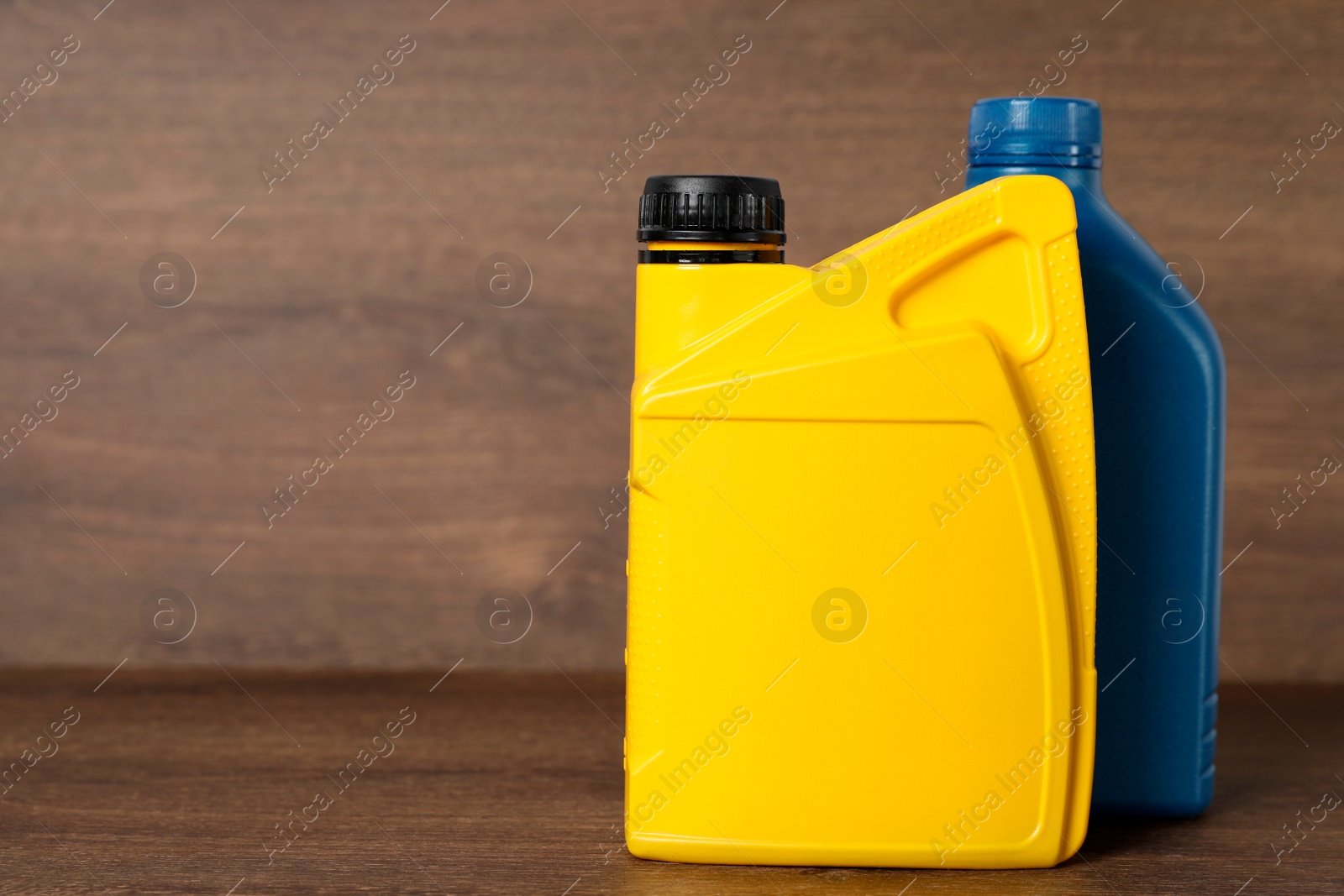 Photo of Motor oil in different canisters on wooden background, space for text