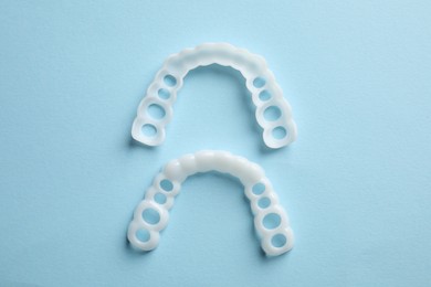 Dental mouth guards on light blue background, flat lay. Bite correction