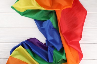 Photo of Rainbow LGBT flag on white wooden table, top view