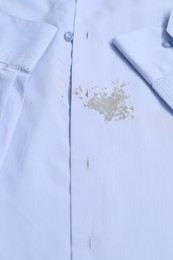 Closeup view of light blue shirt with stain