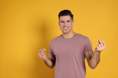 Photo of Handsome man snapping fingers on yellow background. Space for text