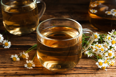 Photo of Cup of tea and chamomile flowers on wooden table