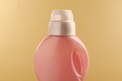 Photo of Bottle with detergent on beige background, closeup