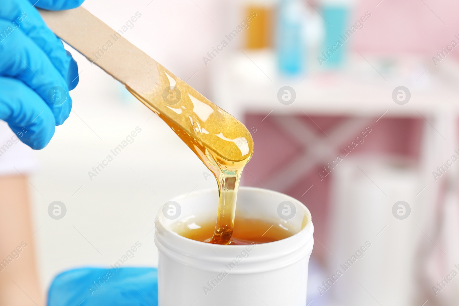 Photo of Woman with wooden stick and sugaring paste indoors, closeup