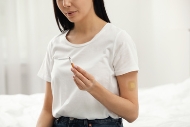 Photo of Young woman with nicotine patch and cigarette in bedroom, closeup