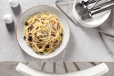 Delicious pasta with anchovies, olives and parmesan cheese served on grey marble table indoors, flat lay