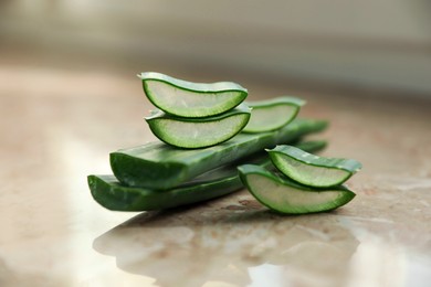 Photo of Green aloe vera leaves and slices on marble table, closeup
