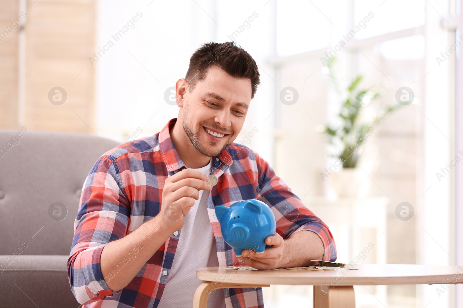 Photo of Man with piggy bank and money at home