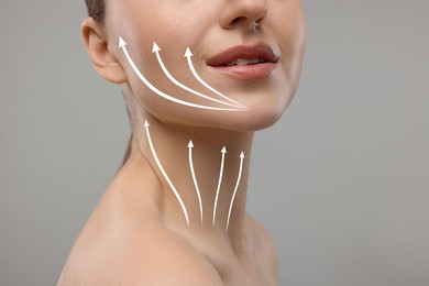 Woman with perfect skin after cosmetic treatment on grey background, closeup. Lifting arrows on her neck and face