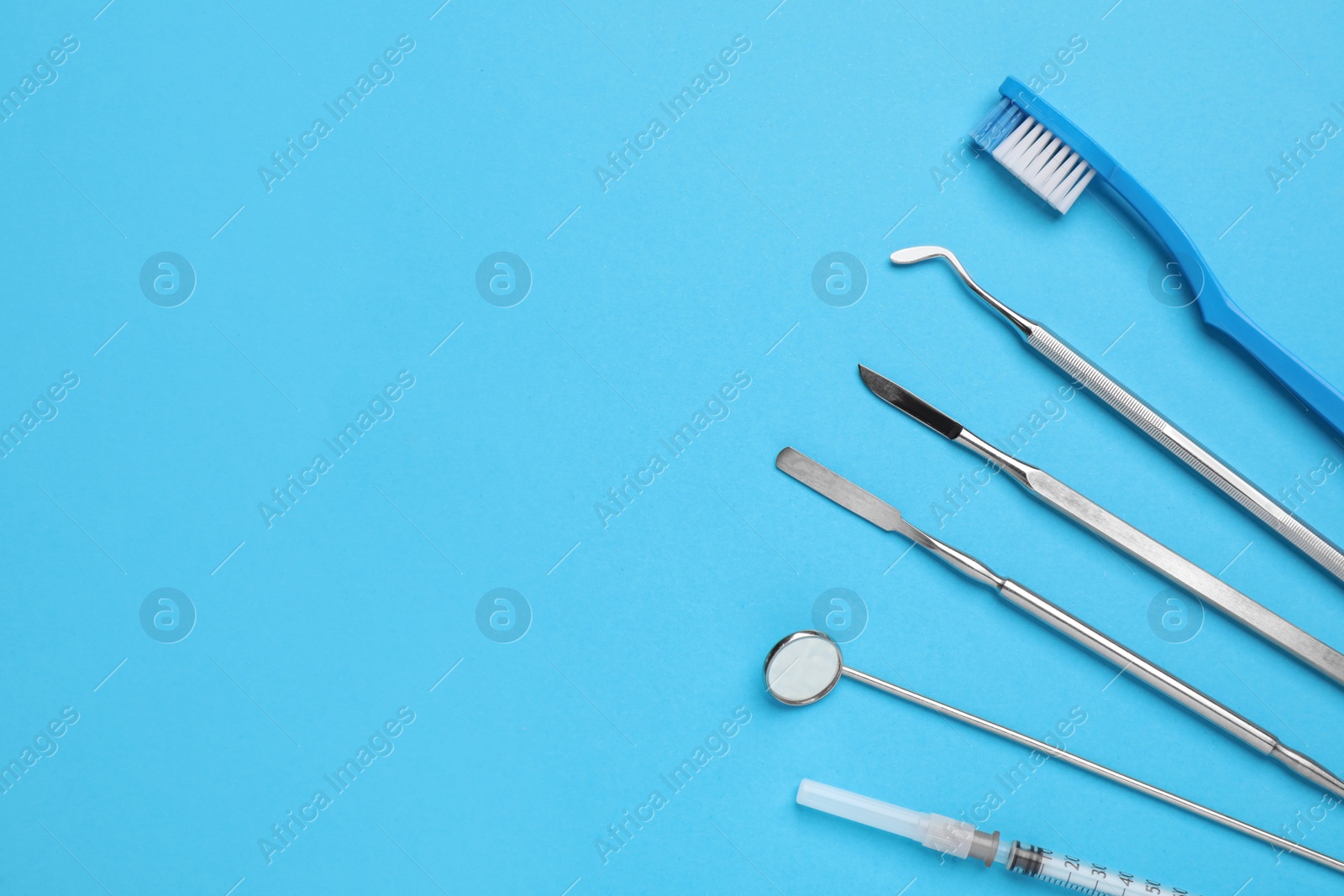 Photo of Set of different dentist's tools, toothbrush and syringe on light blue background, flat lay. Space for text