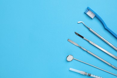 Photo of Set of different dentist's tools, toothbrush and syringe on light blue background, flat lay. Space for text