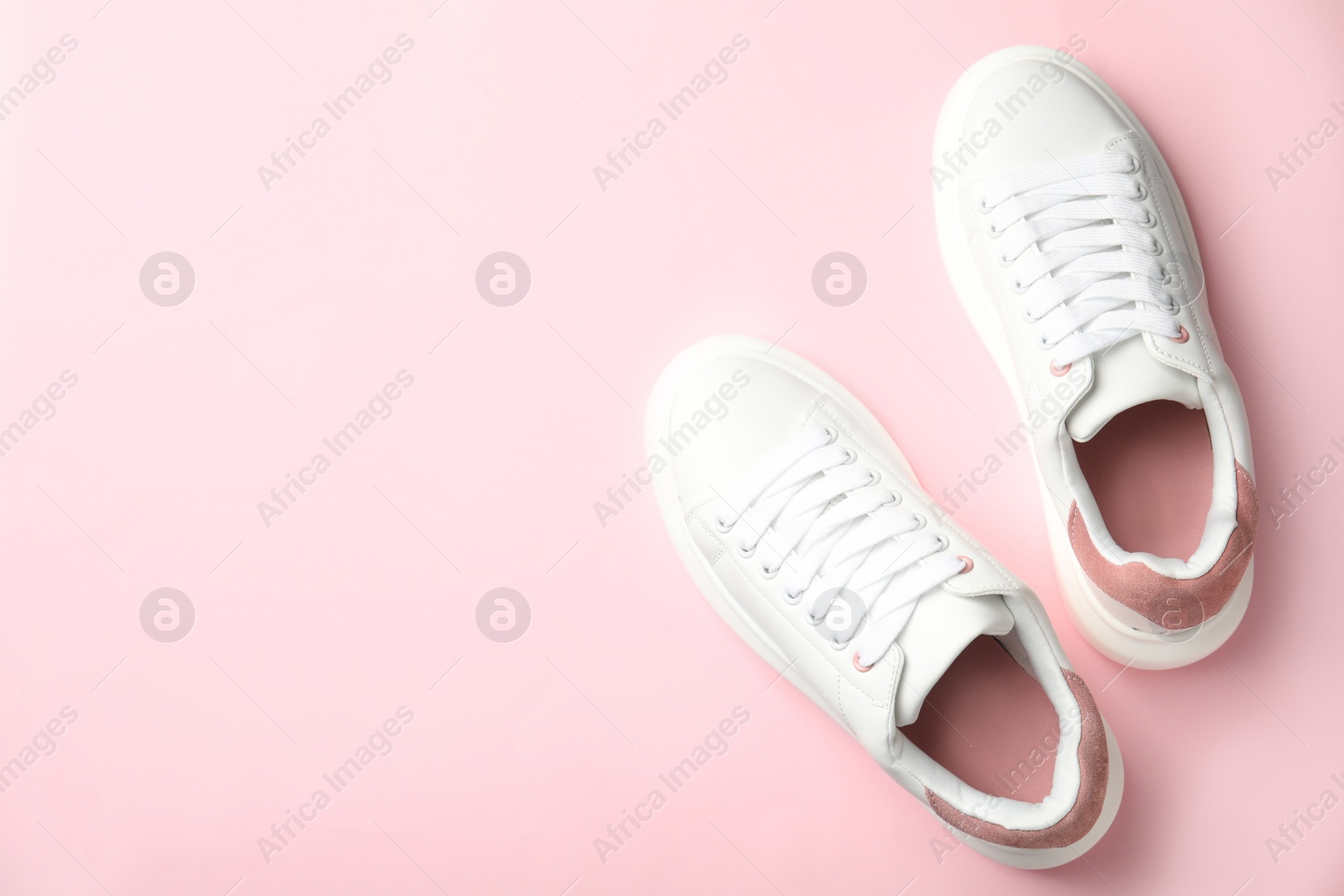 Photo of Stylish white sneakers on pink background, top view. Space for text