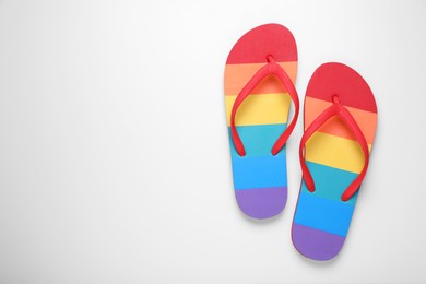 Photo of Stylish rainbow flip flops on white background, top view. Space for text