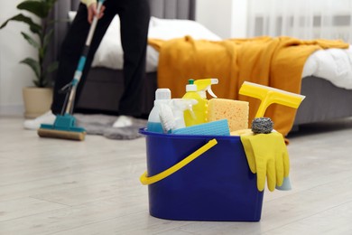 Woman cleaning floor, focus on different supplies in bucket at home