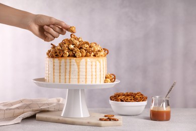 Photo of Woman decorating caramel drip cake at light table, closeup. Space for text