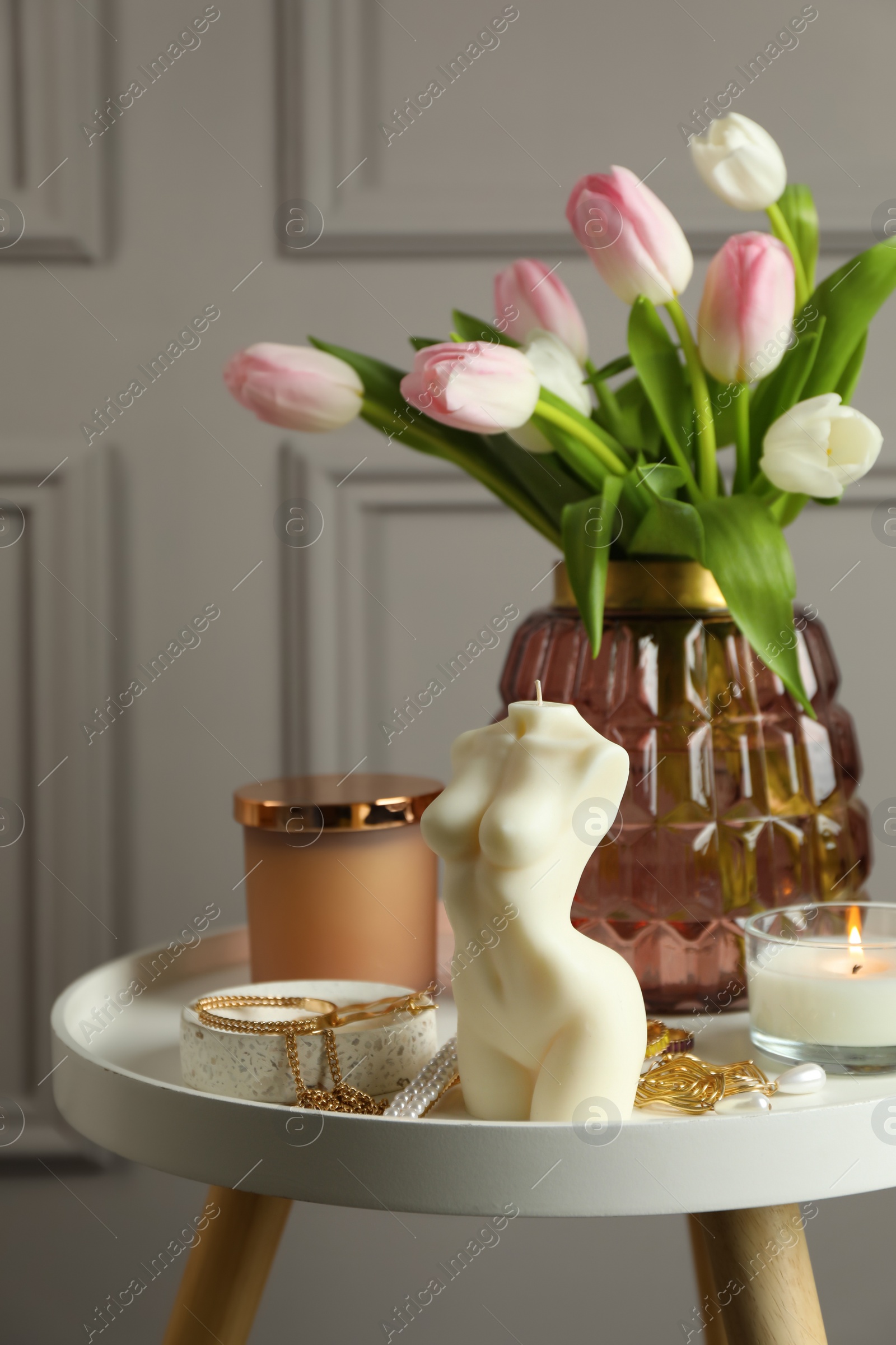 Photo of Beautiful female body shape candle, flowers and decor on white table