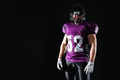 Photo of American football player wearing uniform on dark background. Space for text