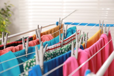 Photo of Clean laundry hanging on drying rack indoors, closeup