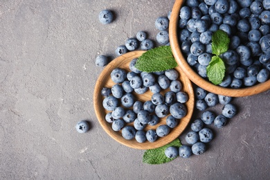 Photo of Flat lay composition with juicy blueberries and green leaves on color table. Space for text