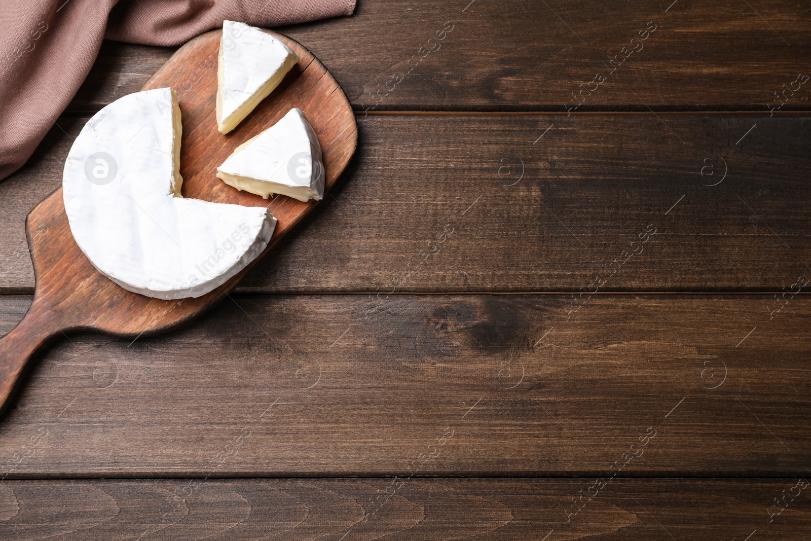 Photo of Board with delicious cheese on wooden table, flat lay. Space for text