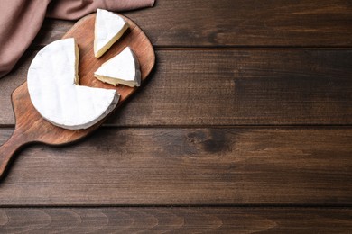 Board with delicious cheese on wooden table, flat lay. Space for text