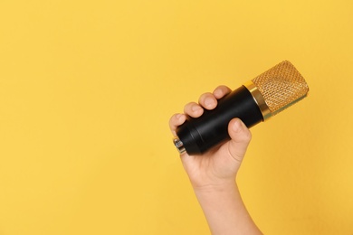 Photo of Child holding microphone on color background, closeup of hand. Space for text