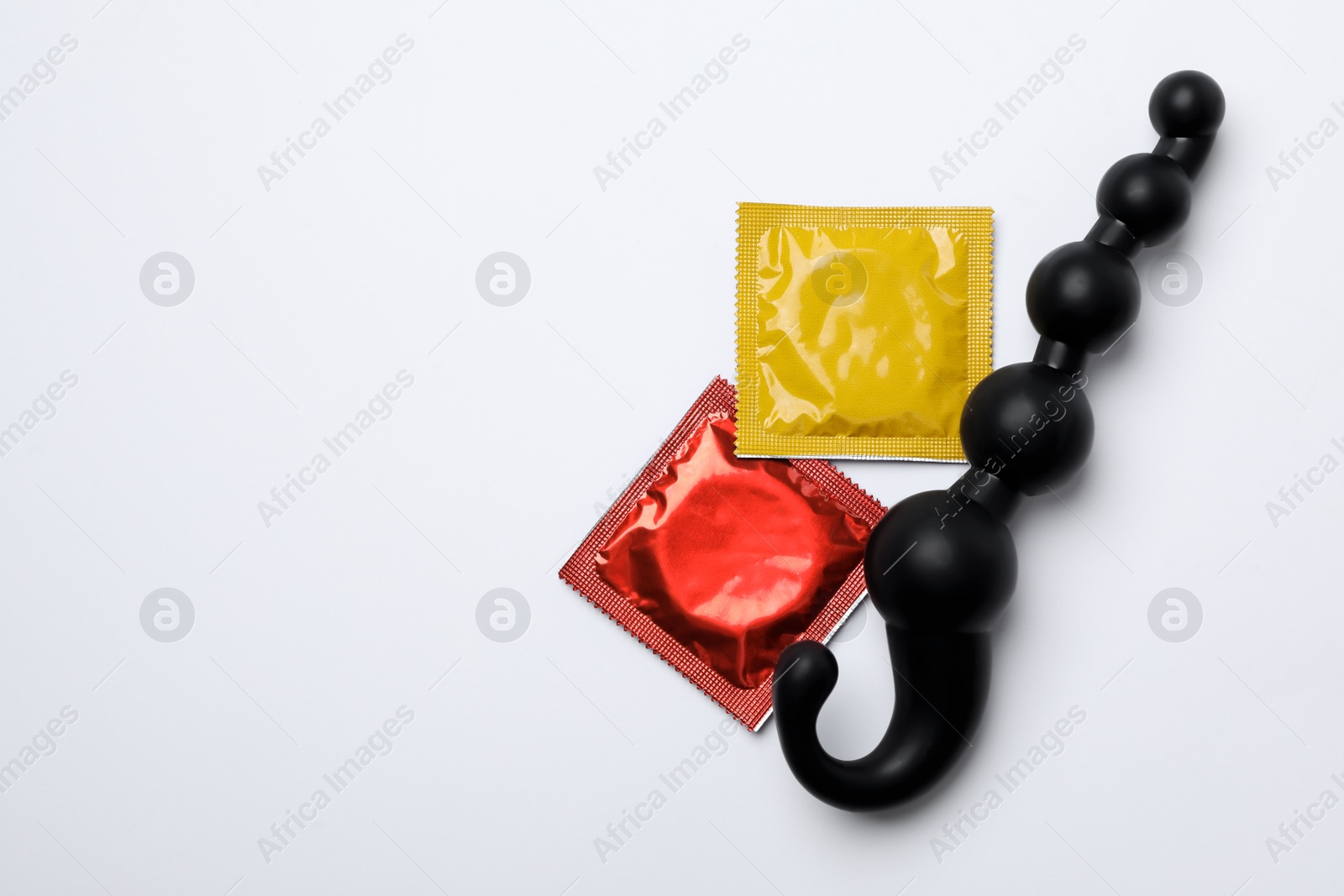 Photo of Anal ball beads and condoms on white background, top view. Sex game