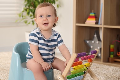 Photo of Little child with abacus sitting on plastic baby potty indoors. Space for text