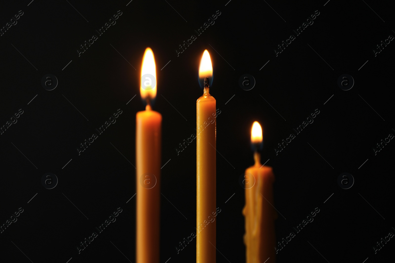 Photo of Burning candles on dark background. Symbol of sorrow