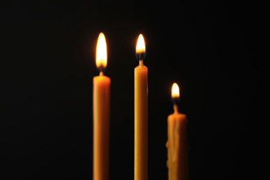 Photo of Burning candles on dark background. Symbol of sorrow