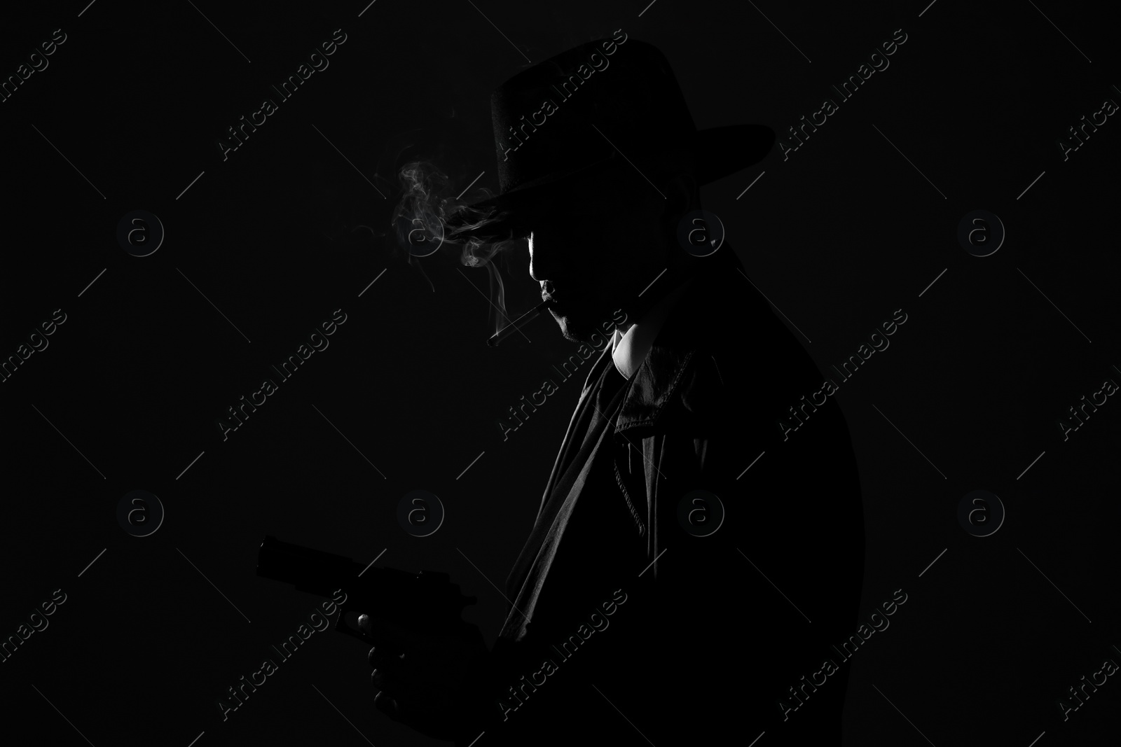 Photo of Old fashioned detective with gun smoking cigarette on dark background, black and white effect