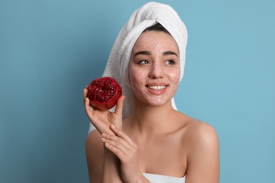 Photo of Woman with pomegranate face mask and fresh fruit on light blue background