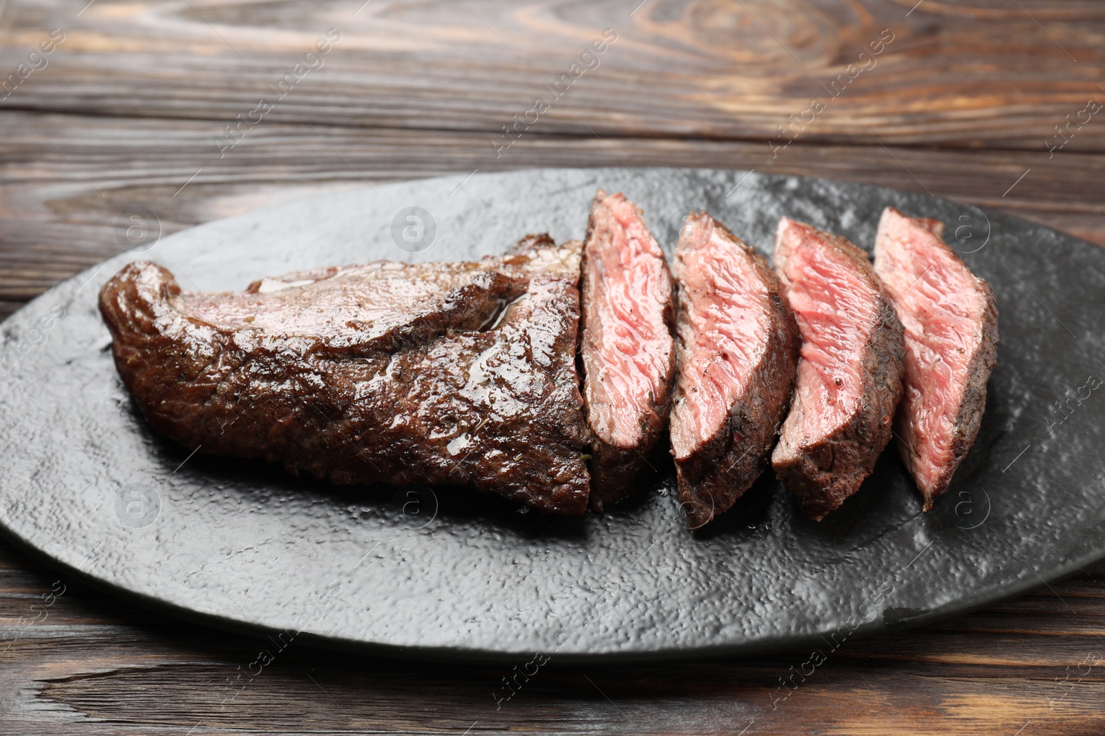 Photo of Pieces of delicious grilled beef meat on wooden table, closeup