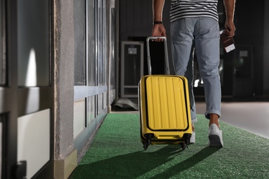 Man with yellow travel suitcase in airport