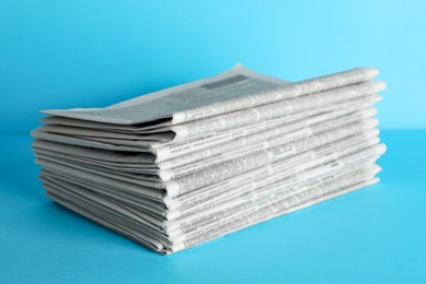 Stack of newspapers on light blue background. Journalist's work