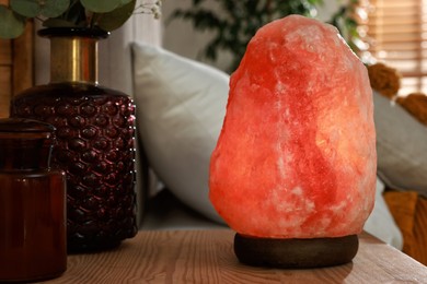 Photo of Beautiful Himalayan salt lamp on wooden nightstand in bedroom