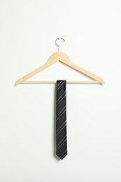 Photo of Hanger with striped necktie on white wall