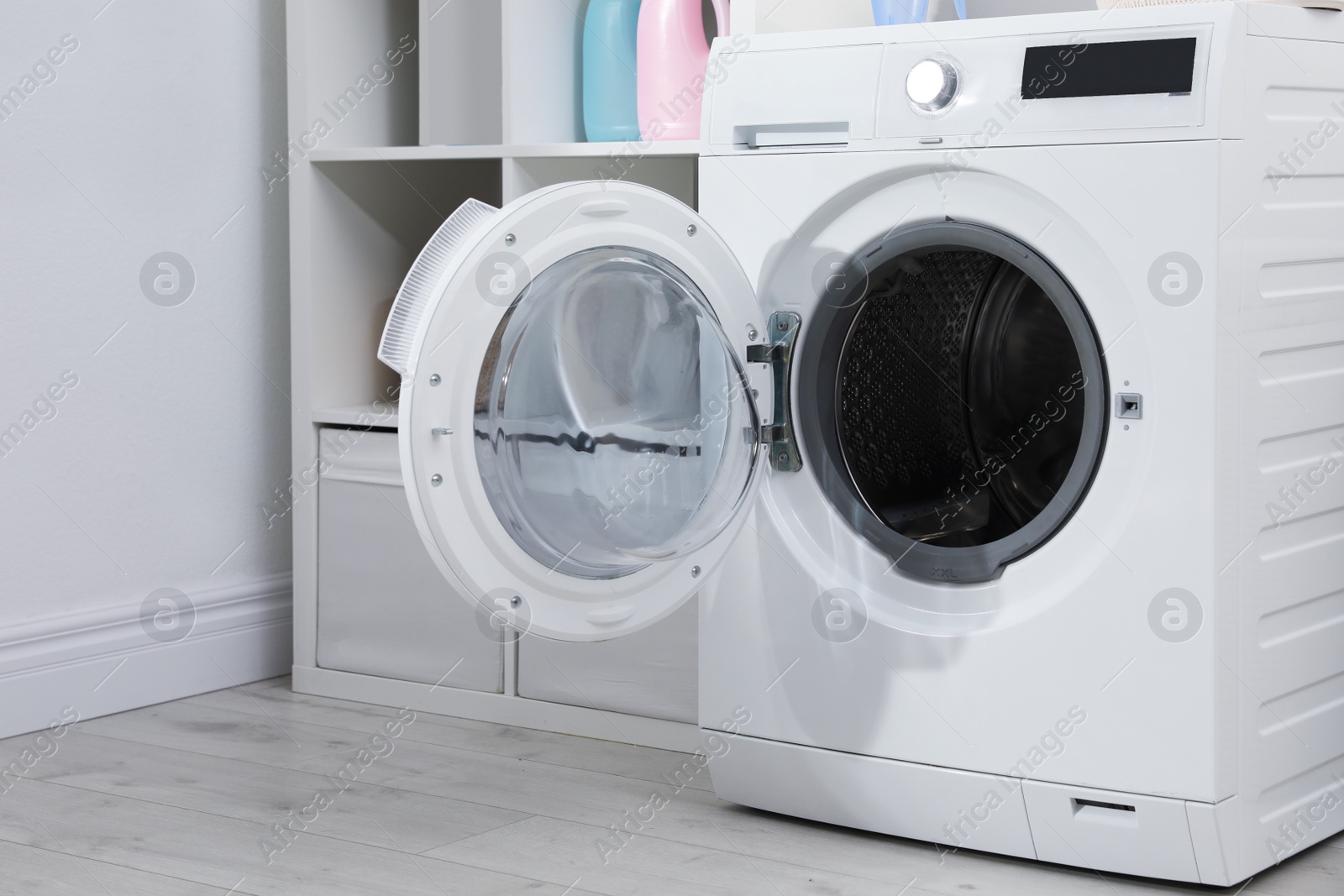 Photo of Modern washing machine in light laundry room