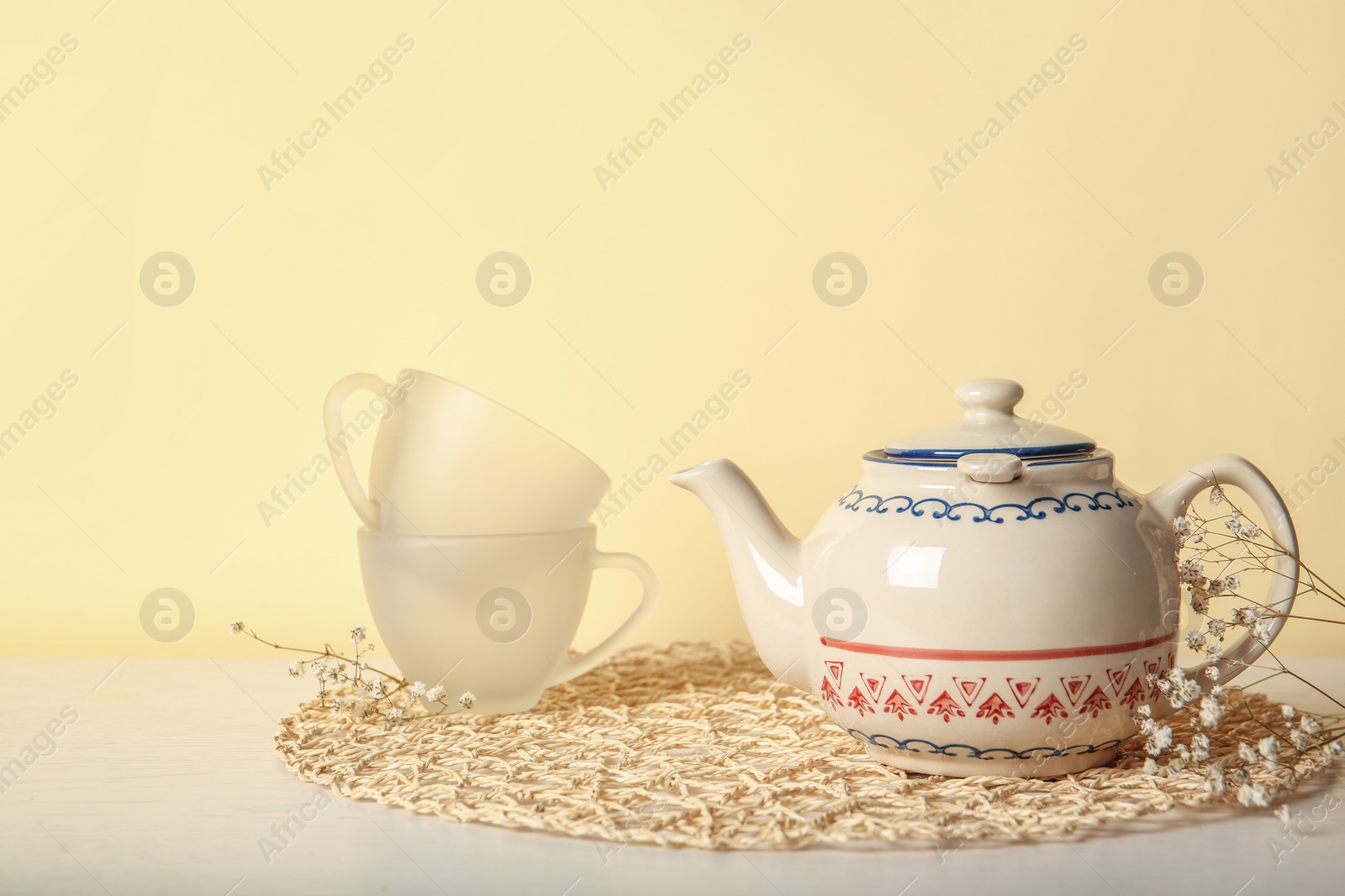 Photo of Teapot and cups on table against color background