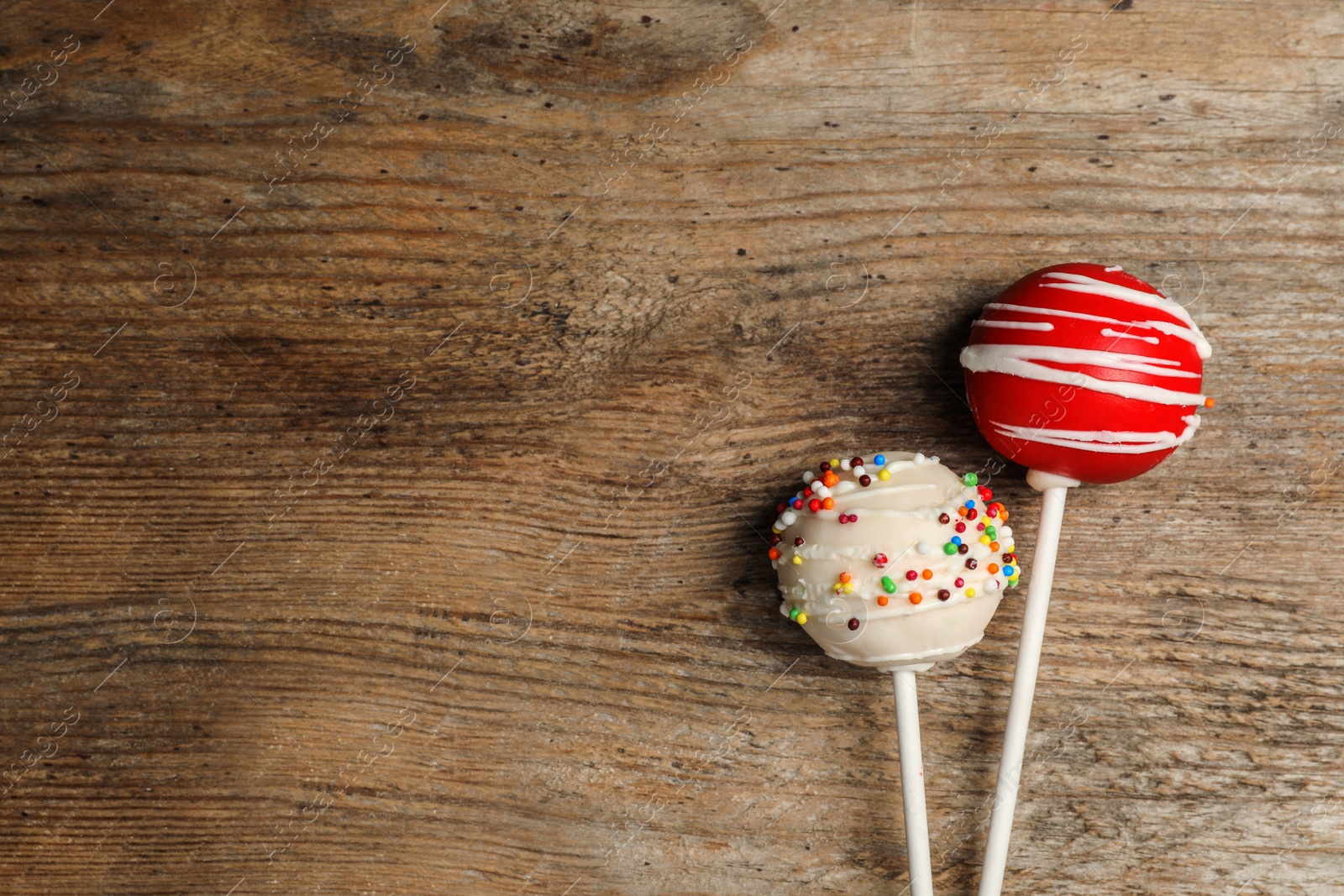 Photo of Bright delicious cake pops on wooden table, flat lay. Space for text