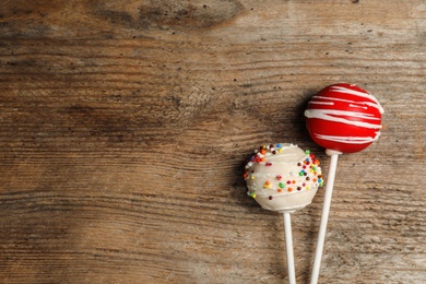 Bright delicious cake pops on wooden table, flat lay. Space for text