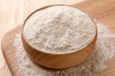 Photo of Quinoa flour in bowl on wooden table, closeup