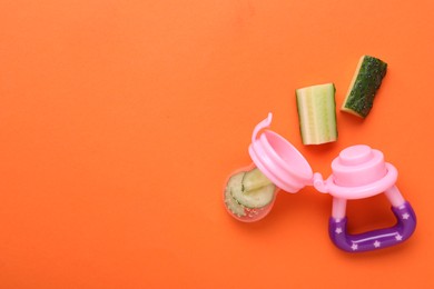 Photo of Nibbler with fresh cucumber on orange background, flat lay. Space for text